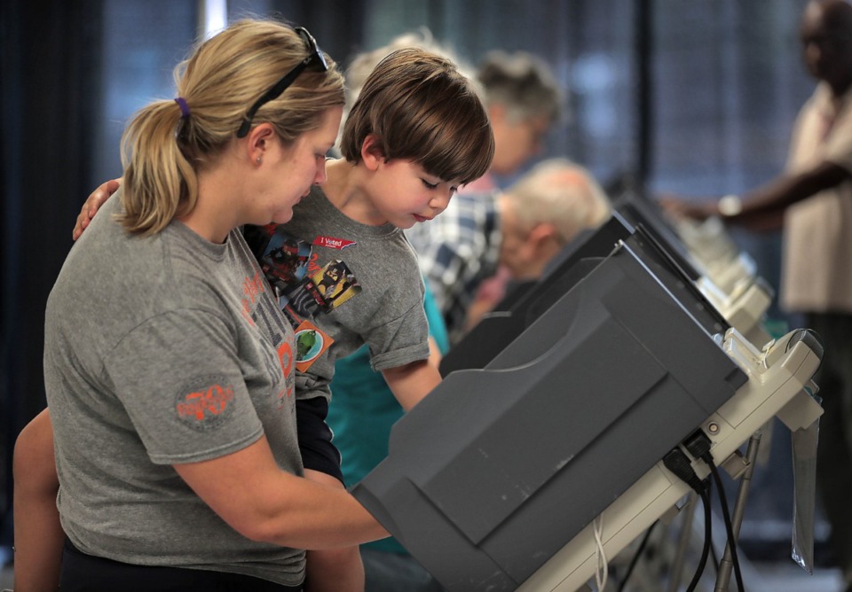 <strong>Katherine Riederer (left) lets Will Riederer, 4, push the button to cast her final ballot at Mississippi Boulevard Christian Church. Memphians turned out to vote on a number of local elections on Oct. 3, 2019 including a sales tax increase, City Council races and a contentious mayoral race.</strong> (Jim Weber/Daily Memphian)