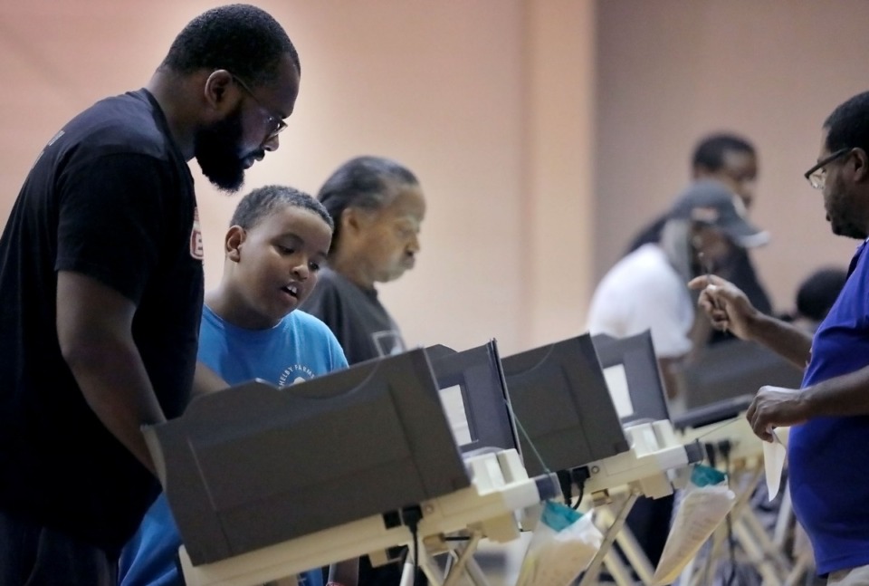 <strong>Mustafa Shaw watches as his father Malik Shaw (far left) casts his vote at the Dave Wells Community Center gymnasium polling location on Oct. 3, 2019.</strong> (Patrick Lantrip/Daily Memphian)