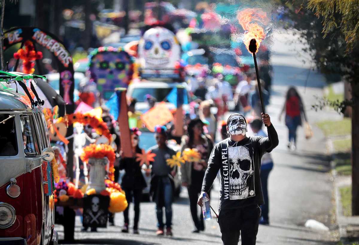 <strong>Carlos Valverde (right) escorts the Dia de los Muertos (Day of the Dead) parade from Overton Square to Overton Park on Oct. 27, 2018. The parade and fiesta are put on by the Brooks Museum of Art and Cazateatro Bilingual Theatre Group drawing from the Latin American tradition of honoring ancestors and celebrating the cycle of life and death.</strong> (Jim Weber/Daily Memphian)