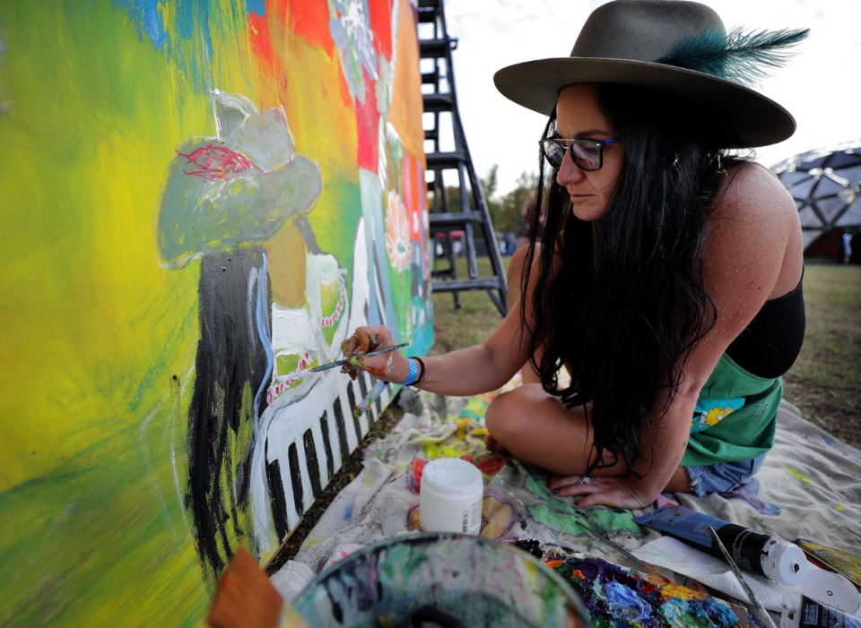 <strong>Kristen Allen, a painter hired by the Mempho Music Fest, works on her piece while singing along to Margo Price's performance during the music festival at Shelby Farms on Oct. 19, 2019.</strong> (Patrick Lantrip/Daily Memphian)