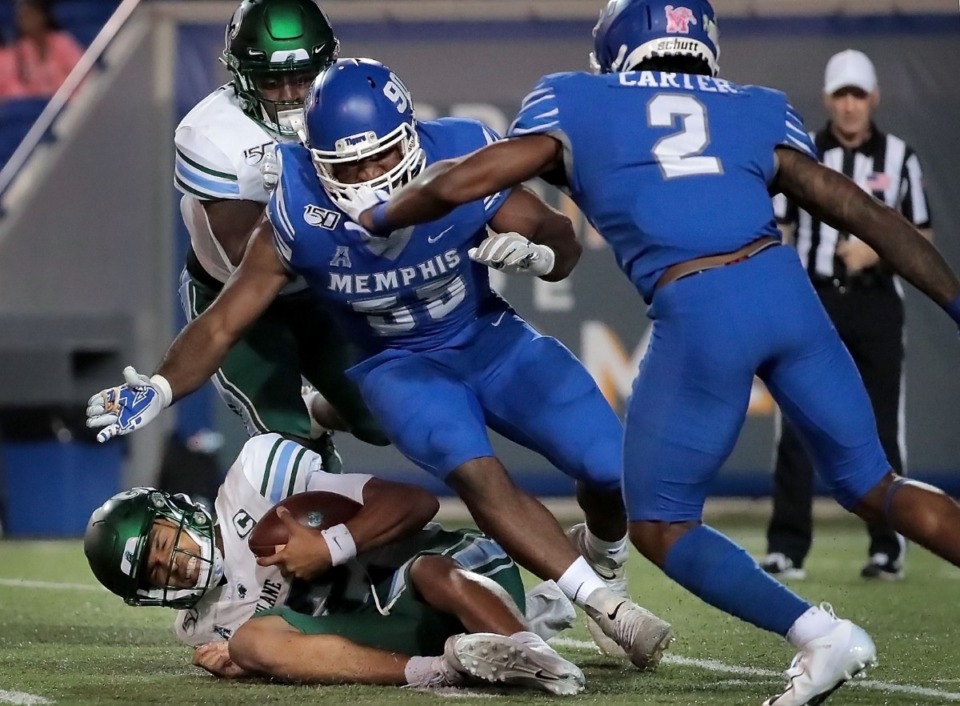 <strong>University of Memphis defenders Bryce Huff (55) and T.J. Carter (2) take down Tulane's quarterback Justin McMillan for a sack during the Tigers game on Oct. 19, 2019, against the Green Wave at Liberty Bowl Memorial Stadium in Memphis.</strong> (Jim Weber/Daily Memphian)