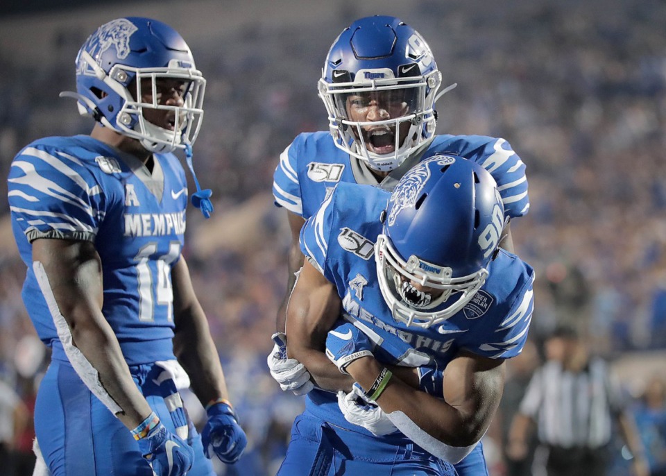 <strong>University of Memphis receiver Calvin Austin III (bottom) celebrates a touchdown with Damonte Coxie and Antonio Gibson (left) during the Tigers game on Oct. 19, 2019, against the Green Wave at Liberty Bowl Memorial Stadium in Memphis.</strong> (Jim Weber/Daily Memphian)