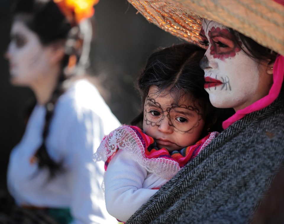 <strong>Quetzaly Najera (2) cuddles with Alejandra Najera during the Dia de los Muertos (Day of the Dead) parade from Overton Square to Overton Park on Nov. 2, 2018. The parade and festival are put on by the Brooks Museum of Art and Cazateatro Bilingual Theatre Group drawing from the Latin American tradition of honoring ancestors and celebrating the cycle of life and death.</strong>(Jim Weber/Daily Memphian)