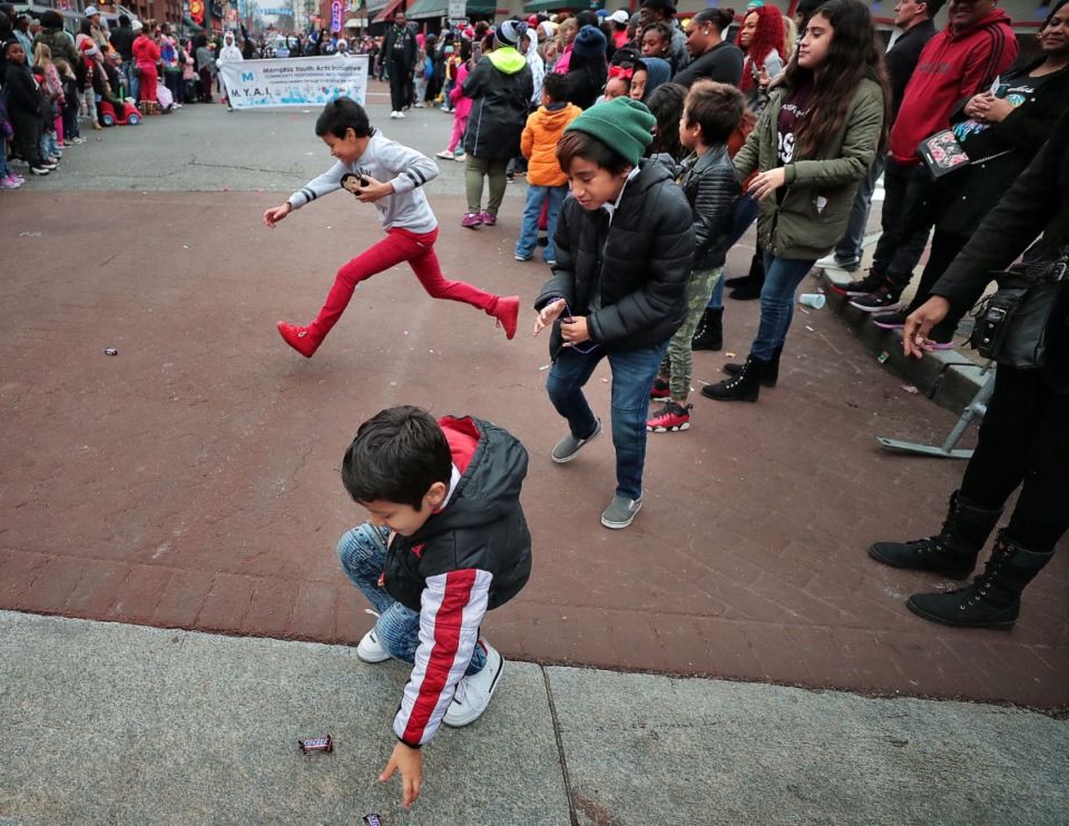<strong>Children dash past the barricade to nab candy during the 2019 Memphis Holiday Parade on Dec. 14, 2019. The parade brought thousands to Beale Street to watch dancers, bands, floats, classic cars and Santa usher in the holiday season.</strong> (Jim Weber/Daily Memphian)