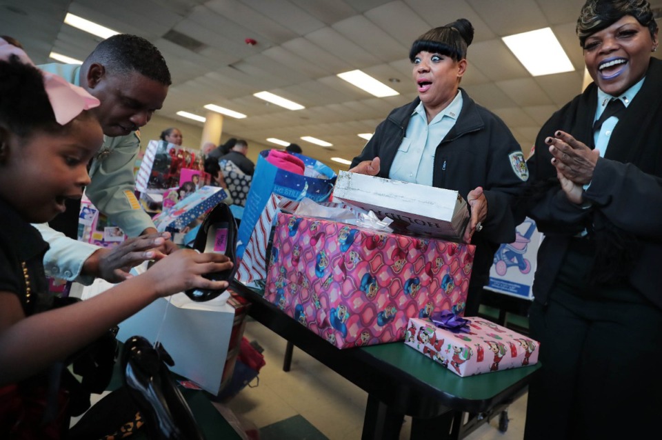<strong>Sgt. Johnnie Brown (center) and Lt. Kim Lee (right) have almost as much fun as kindergartner Lia Sullivan while opening presents on Thursday, Dec. 19, at Vollentine.</strong> (Jim Weber/Daily Memphian)