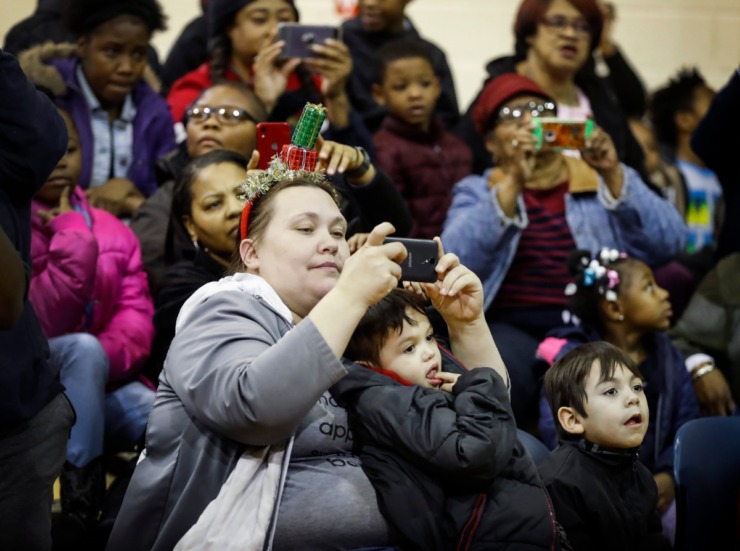 <strong>While holding her son Pablo Perez, 2, Angela Horn (left) takes a picture of the Memphis men's basketball team during a toy giveaway on Dec. 20, 2019, at the Davis Community Center.</strong> (Mark Weber/Daily Memphian)