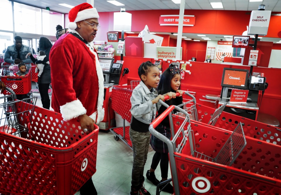 <strong>August Latham, 7 (middle), prepares for a holiday shopping spree with friend Genesis Malone, 7, (right) and volunteer Pastor Ricky Floyd at Target Dec. 23. Actress Carrie Bernans and reality television show star Candace Rice, both of Memphis, gave 28 Memphis-area children a shopping spree for Christmas.</strong> (Mark Weber/Daily Memphian)