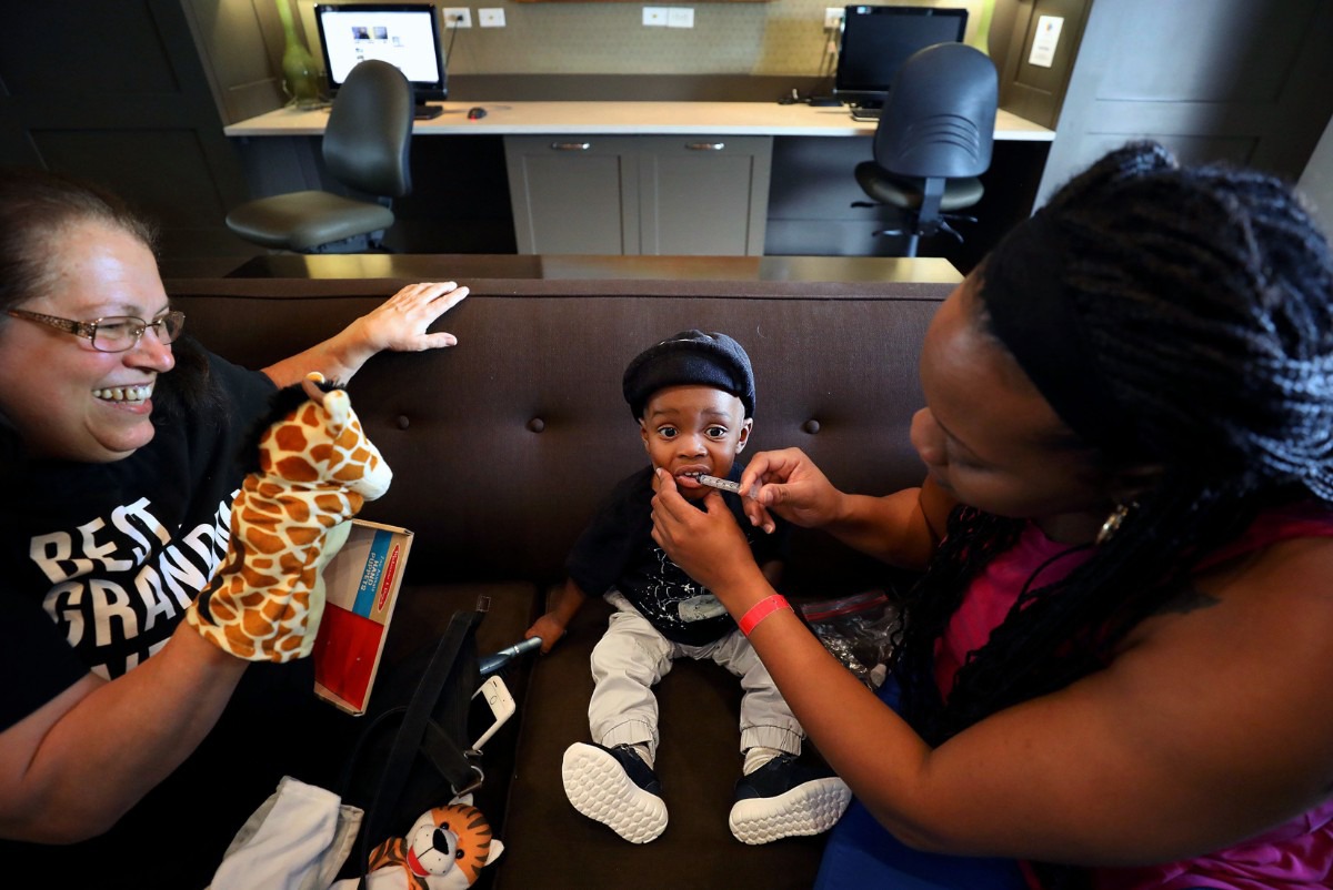 <strong>Nicole Box gives son Zanick Masters a dose of medicine while Joanie Bergstrom tries to entertain the 13-month-old at the FedEx Family House on May 31, 2019. Box, who lives in Jamaica, brought her son to Memphis to get treatment for a congenital heart defect known as anomalous left coronary artery from the pulmonary artery or ALCAPA.</strong> (Patrick Lantrip/Daily Memphian)