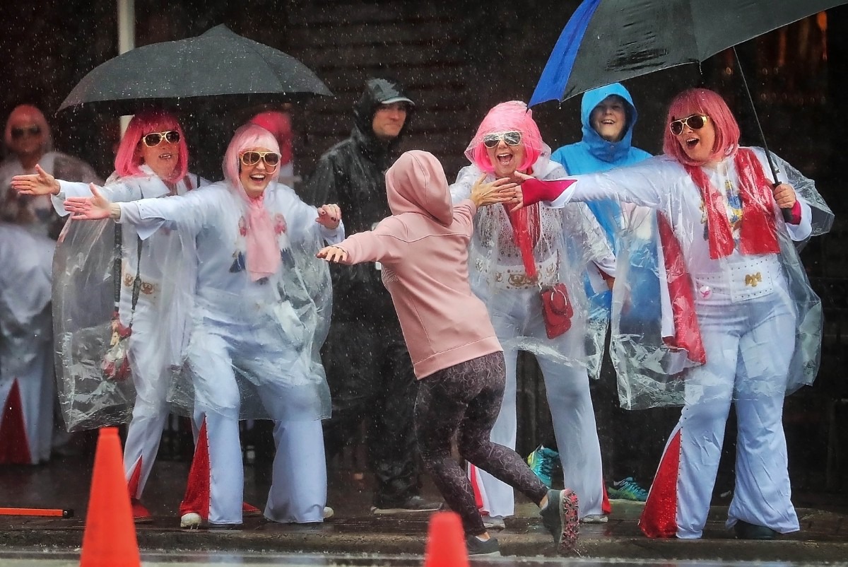 <strong>The King's Queens, whose motto is "Taking Care of Boobies," cheer on runners entering the final stretch as breast cancer survivors, dedicated friends and family brave the heavy rain falling on Downtown Memphis to participate in the annual Susan G. Komen Race for the Cure on Oct. 26, 2019, to raise money to fund research, education, screening and treatment of breast cancer.</strong> (Jim Weber/Daily Memphian)