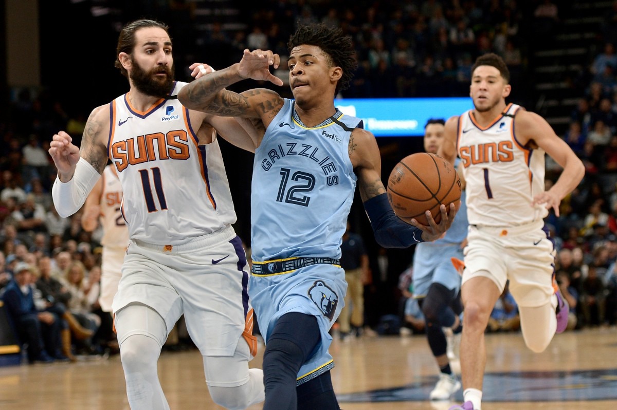 <strong>Memphis Grizzlies guard Ja Morant (12) drives ahead of Phoenix Suns guards Ricky Rubio (11) and Devin Booker (1) in the first half of an NBA basketball game Sunday, Jan. 26, 2020, at FedExForum.</strong> (Brandon Dill/AP)