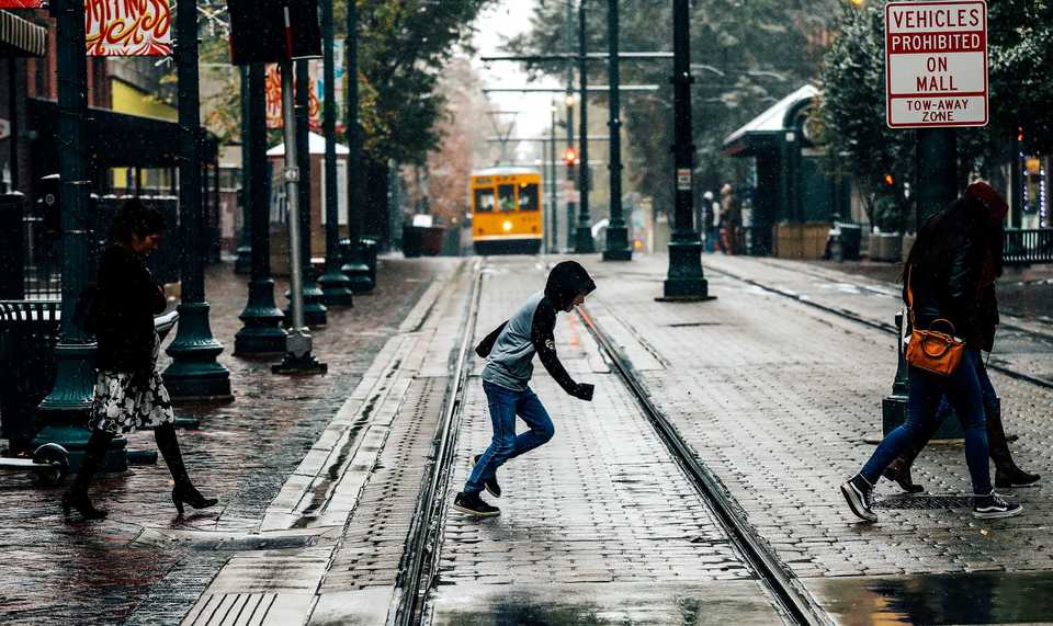 <strong>A pedestrian dashes across the Main Street trolley tracks as a dusting of snow falls Nov. 14, 2018. Some Memphis-area schools closed early and churches canceled their evening activities as the wintry mix of sleet and snow passed through the Mid-South.</strong> (Houston Cofield/Daily Memphian)