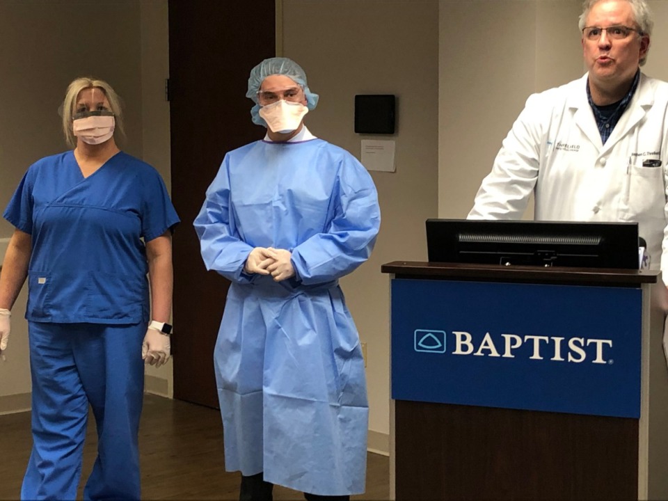 <strong>Dr. Stephen Threlkeld (at podium) shows the protective gear that staff working with COVID-19 patients wear at Baptist Memorial Hospital during a press conference Monday, March 9. In announcing a confirmed case locally, Threlkeld said only that the patient was in good condition and was in a negative-pressure room at the hospital. He would not release other information and asked others to abide by the same rules.</strong> (Jane Roberts/Daily Memphian)