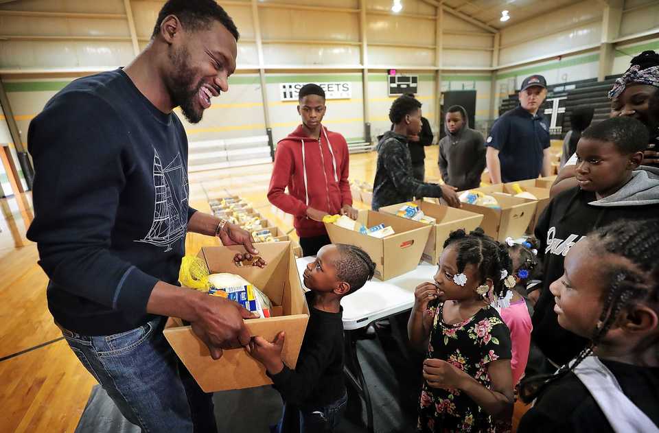 <strong>Zamarion Boyd, 5, argues with former Memphis Grizzlies player Tony Allen (left) that he is big enough to carry the turkey as the Grindfather greets families in person while passing out Thanksgiving meals at Streets Ministries on Nov. 17, 2018.</strong> (Jim Weber/Daily Memphian)