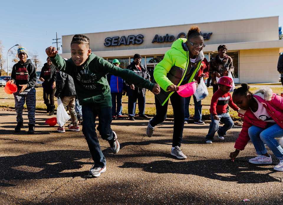<strong>Eric Milligan (left), 9, runs onto Elvis Presley Boulevard to snatch up some candy during the Whitehaven Christmas Parade on Saturday, Nov. 17, 2018. The parade is in its 21st year and drew over 4,000 attendees. Just under 200 schools, nonprofits and other organizations participated in the 2018 parade, one of several outreach initiatives held by the Academy for Youth Empowerment.</strong> (Houston Cofield/Daily Memphian)