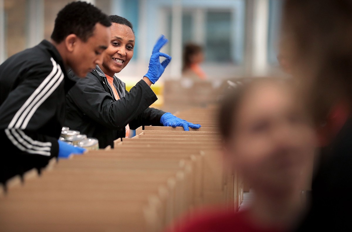 <strong>Alem Worku signals down the line as volunteers gather in groups of 10 to work an assembly line on March 17, 2020, at the Midsouth Food Bank warehouse, where they were putting together 14-day food kits for needy families in Memphis. The Food Bank is trying to assemble 50,000 kits consisting of 25 pounds of canned vegetables, canned fruit, peanut butter, oatmeal and rice to feed families that may be forced into isolation by COVID-19.</strong> (Jim Weber/Daily Memphian)