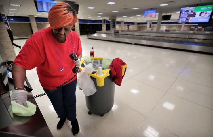 <strong>Janitorial contractor Angela Jones wipes down phones and handrails in the deserted baggage claim area at Memphis International Airport on March 13, 2020. In addition to adding more cleaning staff to clean and disinfect, the airport has temporarily closed the C terminal checkpoint as well as Maggie O'Shea's and Moe's Southwestern Grill restaurants because passenger numbers have fallen significantly below projections during an expected spring break peak time due to COVID-19</strong>. (Jim Weber/Daily Memphian)