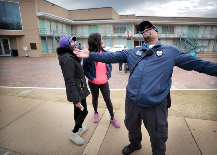 <strong>Terrance Miller, a member of the Blue Suede Brigade, jokes with spring breakers Devina Lias (left) and Cherish Bridges in front of the National Civil Rights Museum on March 13, 2020. Miller is looking at a serious loss of income from his side gig with FedExForum security as sporting events and concerts get cancelled due to COVID-19.</strong> (Jim Weber/Daily Memphian)