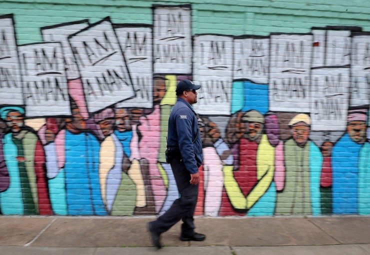<strong>Terrance Miller, a member of the Blue Suede Brigade, passes by the "I am a man" mural on South Main while walking his route near the National Civil Rights Museum on March 13, 2020. Miller is looking at a serious loss of income from his side gig with FedExForum security as sporting events and concerts get cancelled due to COVID-19.</strong> (Jim Weber/Daily Memphian)