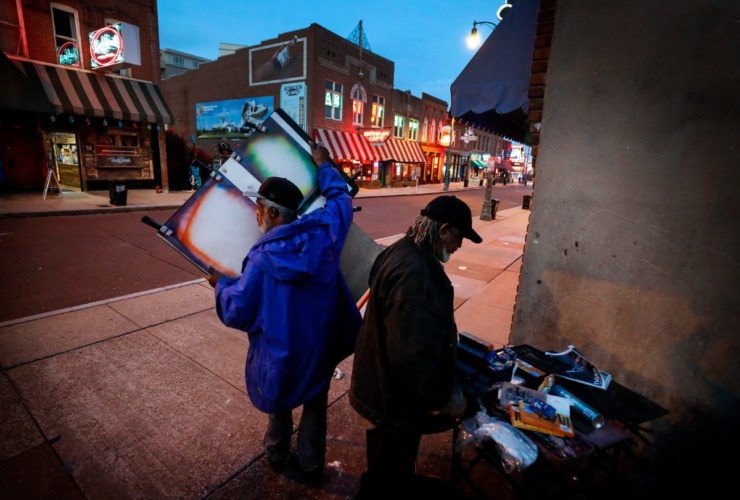 <strong>Artist Carl Brown (left) and Ernest Lawson (right) pack up their supplies around 7:30 p.m. on St. Patrick's Day Tuesday, March 17, 2020 on Beale Street. Smaller crowds forced the the pair to head home hours before they normally would.</strong> (Mark Weber/Daily Memphian)