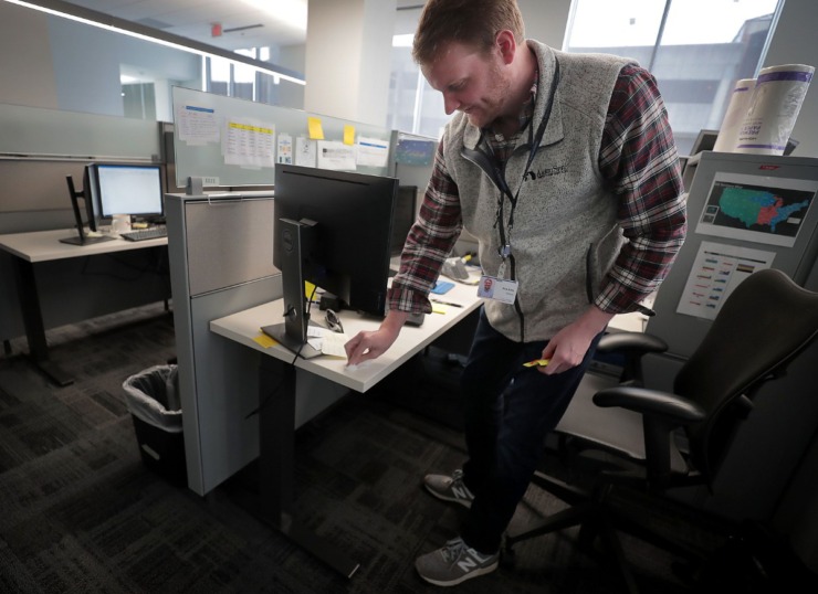 <strong>ServiceMaster employee Nick Eddy disinfects his cubical with bleach wipes at the ServiceMaster headquarters in Downtown Memphis on March 17, 2020, as many corporations shift to working remotely and others ramp up their cleaning regimen due to COVID-19.</strong> (Jim Weber/Daily Memphian)