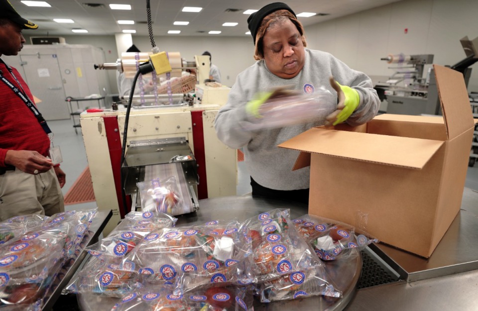 <strong>Deltha Earnest boxes up shrink-wrapped packages as food prep workers at the SCS Nutrition Services center sort meals slated for delivery to a local community center on March 18, 2020. The SCS Nutrition Services Center will be ramping up production next week as the school district makes plans to distribute meals from some 60 sites that students on the school lunch program will be able to take home.&nbsp;</strong>(Jim Weber/Daily Memphian)
