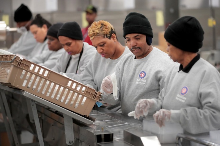 <strong>Claudia Diggs (right), Stanley Cooke and Jennifer Dennis join a line of food prep workers at the SCS Nutrition Services center to sort meals slated for delivery to a local community center on March 18, 2020. The SCS Nutrition Services Center will be ramping up production next week as the school district makes plans to distribute meals from some 60 sites that students on the school lunch program will be able to take home.&nbsp;</strong>(Jim Weber/Daily Memphian)
