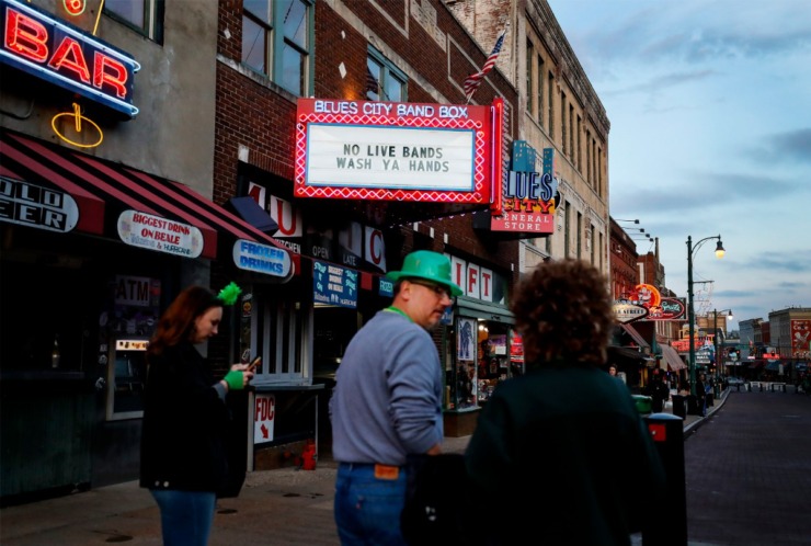 <strong>Tourists celebrating St. Patrick's Day on Beale Street on Tuesday, March 17, 2020, walk by the Blues City Cafe &amp; Band Box billboard stating they temporarily will not have live music.</strong> (Mark Weber/Daily Memphian)
