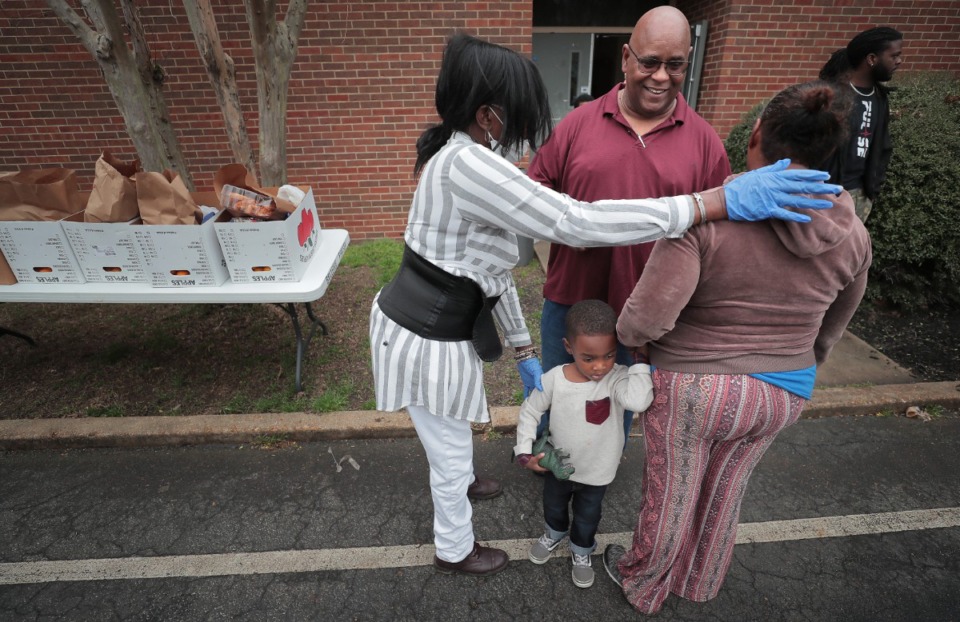 <strong>Brenda Hardy (left) and pastor Doug Williams (center) pray with Sandra Ward and her grandson Carnell Ward as members of the Pursuit of God Church, in partnership with Life Church, Bellevue Baptist and Mid-South Food Bank, assemble some food baskets to give away to those in need on Friday, March 20.</strong> (Jim Weber/Daily Memphian)