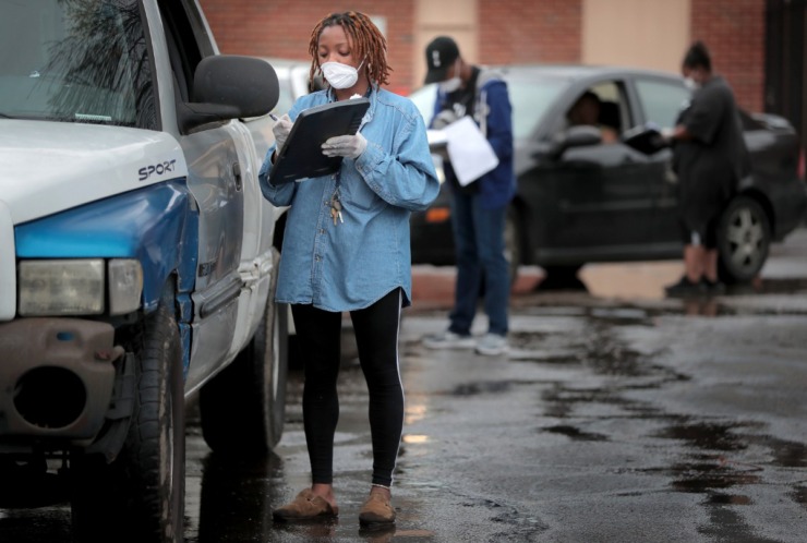 <strong>Christina Floyd gathers information during a drive-through food drive as members of the Pursuit of God Church in partnership with Life Church, Bellevue Baptist and Mid-South Food Bank assemble some 250 food baskets to give away to those in need on March 20, 2020 at Pursuit of God Church in Frayser.</strong> (Jim Weber/Daily Memphian)