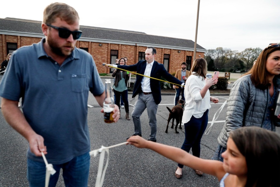 <strong>Lance Horner (middle) uses a tape measure to make sure friends are six feet apart before they surprise bridal couple Holly Whittle and John Steinert after their wedding on Saturday, March 21, 2020, at St. Louis Catholic Church.</strong> (Mark Weber/Daily Memphian)