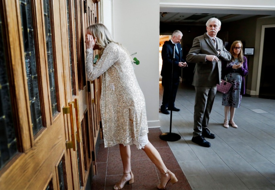 <strong>Bride Holly Whittle (left) looks through a door before her wedding to John Steinert on Saturday, March 21, 2020, at St. Louis Catholic Church. The couple had to pare down their wedding after social distancing was strongly encouraged to decrease the spread of the coronavirus.</strong> (Mark Weber/Daily Memphian)