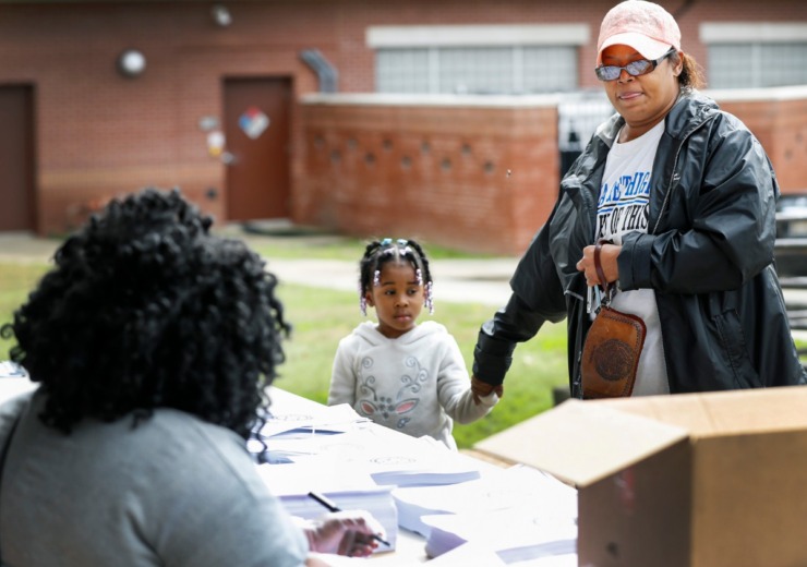 <strong>Sylvia Stewart (right) along with granddaughter Arianna Moore, 4, grab work packets during a Shelby County Schools food distribution event Monday, March 23, 2020 at Orange Mound Community Center.</strong> (Mark Weber/Daily Memphian)