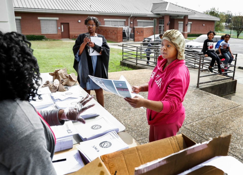 <strong>Parent Dasha Pullen (right) grabs work packet for her children during a Shelby County Schools food distribution event Monday, March 23, 2020 at Orange Mound Community Center.</strong> (Mark Weber/Daily Memphian)