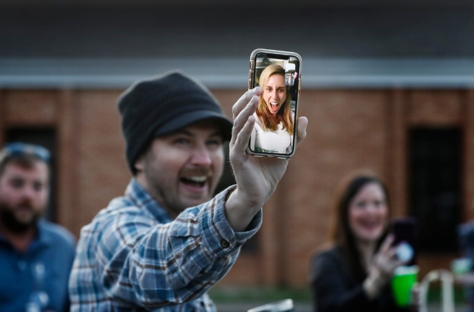 <strong>Logan Abrahams hold a smart phone of a screaming Kristin Barry while they FaceTime during a surprise party for couple Holly Whittle and John Steinert after the couple married on Saturday, March 21, 2020, at St. Louis Catholic Church.</strong> (Mark Weber/Daily Memphian)