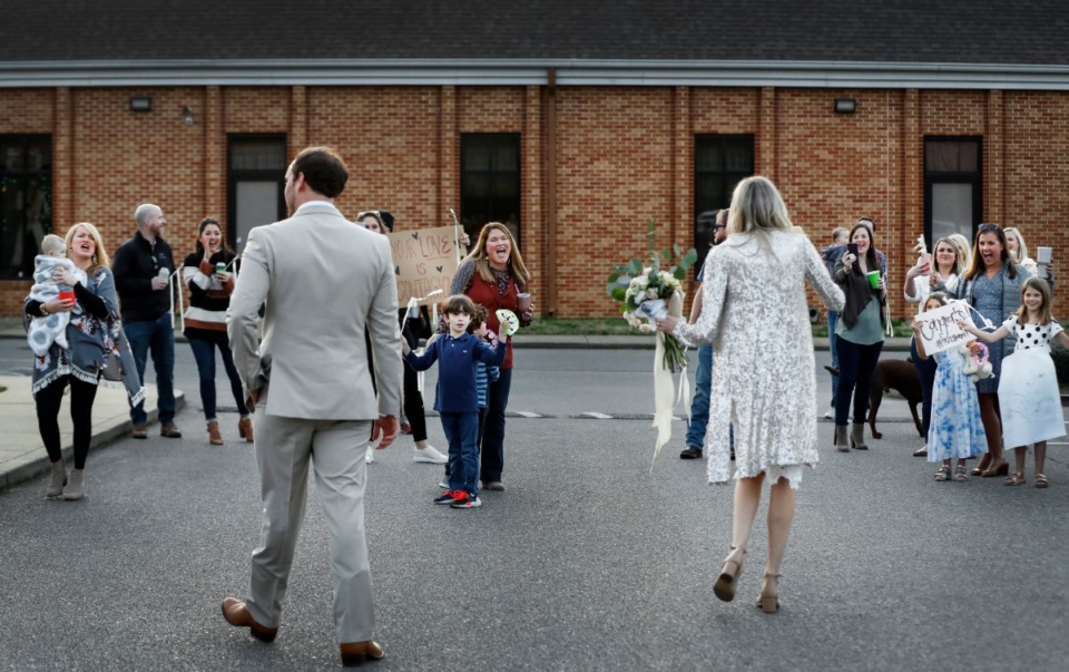 <strong>Newlyweds Holly Whittle and John Steinert celebrate with cheering friends who surprised them in the parking lot after their wedding on Saturday, March 21, 2020, at St. Louis Catholic Church.</strong> (Mark Weber/Daily Memphian)