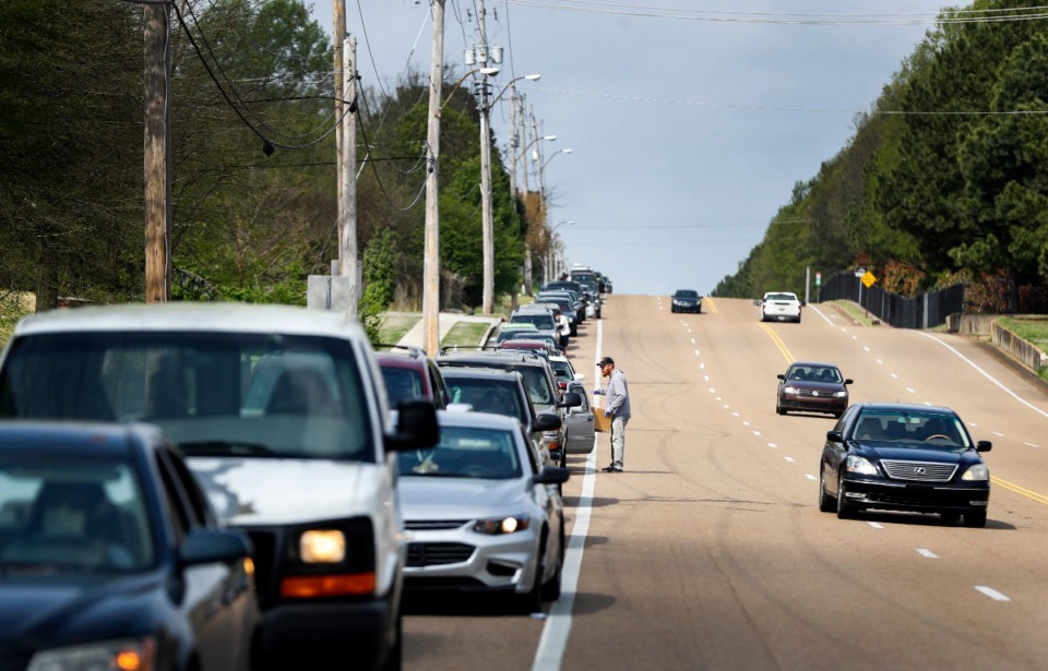 <strong>Memphis Athletic Ministries volunteer Jeff Cage (middle) directs traffic during a drive-through food distribution event on Friday, March 27, 2020. Cars backed up for over a mile, as they waited to grab supplies and food.</strong> (Mark Weber/Daily Memphian)