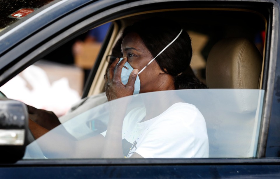 <strong>Gloria Snipes adjuster her facemark while grabbing 14-day food box during a drive-through event at Memphis Athletic Ministries&rsquo; Grizzlies Center on Friday, March 27, 2020.</strong> (Mark Weber/Daily Memphian)