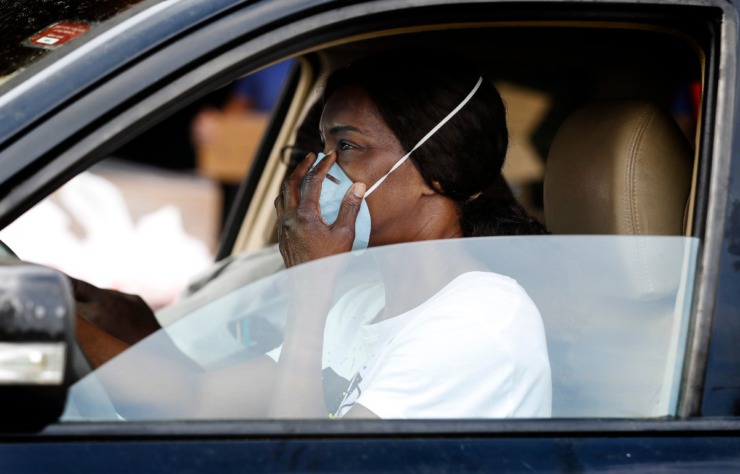 <strong>Gloria Snipes adjusts her facemask while getting a 14-day food box during the drive-thru event at Memphis Athletic Ministries’ Grizzlies Center on Friday, March 27.</strong> (Mark Weber/Daily Memphian)