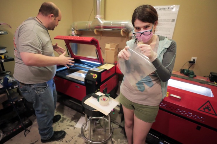 <strong>Renee Timbs (right) and Donngal Mac Ronain with the Midsouth Makers try to figure out the right settings to cut clear plastic without melting it while creating face shields for the Memphis Medical Society on March 29, 2020. The group of tinkerers used 3-D printers to create the frame and a laser cutter to make a matching transparent shield.</strong> (Jim Weber/Daily Memphian)
