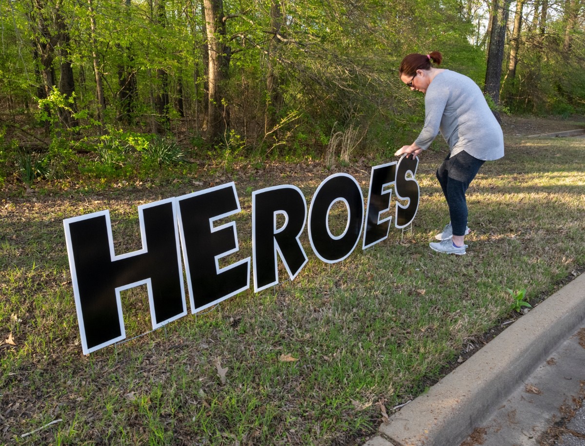 <strong>Krystal Cruise places "Heroes Work Here" sign outside Baptist Memorial Hospital-Collierville, Sunday, March 29, 2020. Citizens showed up at the parking lot Sunday night during shift change to show support to the health care workers.</strong> (Greg Campbell/Special to The Daily Memphian)
