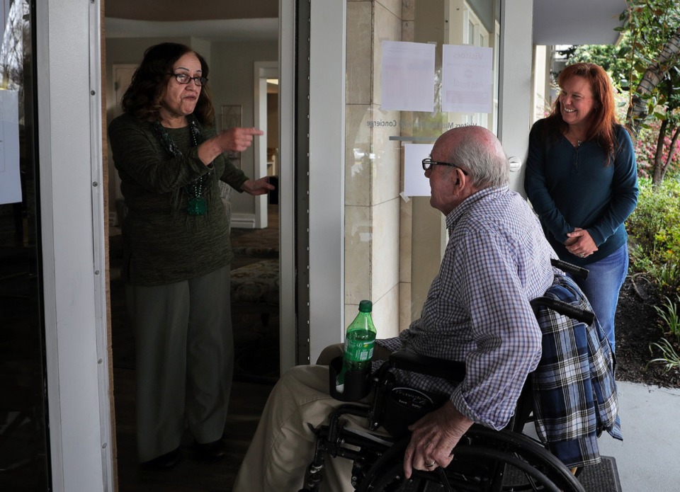 <strong>Iris Depee jokes with Henry Lantrip, a resident of the Glenmary at Evergreen while his daughter Margaret Walker drops him off after a doctor's appointment March 17, 2020. In the light of the coronavirus outbreak, visitors are not permitted inside the assisted living facility.</strong> (Patrick Lantrip/Daily Memphian)