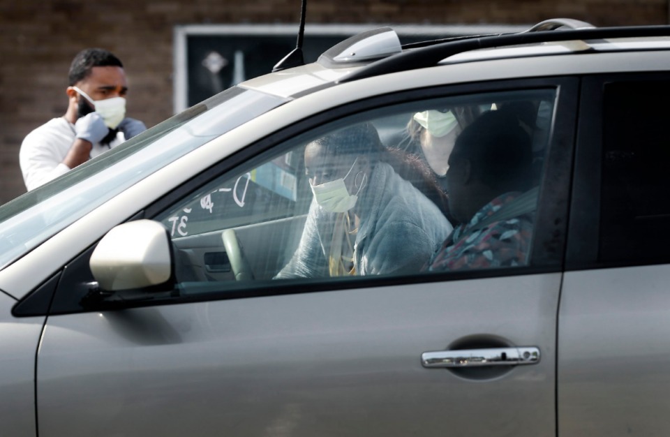 <strong>Mid-South Food Bank volunteer Paulita Edmonson (middle) places supplies in a car during a food distribution event Wednesday, April 1, 2020, on E. Georgia Ave.</strong> (Mark Weber/ The Daily Memphian)
