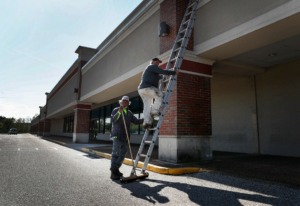 <strong>Roofers Larry Dennis (left) and Glenn Janes (right) descend a ladder after checking the roof of a vacant rental property in Gateway Shopping Center on Thursday, April 2. The U.S. Army Corps of Engineers will build a temporary hospital of non-acute beds at the shopping center to help deal with the expected coming surge in COVID-19 cases.</strong> (Mark Weber/Daily Memphian)