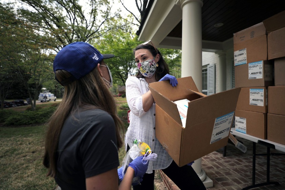 <strong>Stephanie Lepone takes a box of N95 masks from Jill Stockburger outside her East Memphis home April 6, 2020. Lepone, along with roughly 400 other volunteers agreed to help fix some nearly 20,000 masks Baptist Hospital found that were in need of new elastic straps.</strong> (Patrick Lantrip/Daily Memphian)