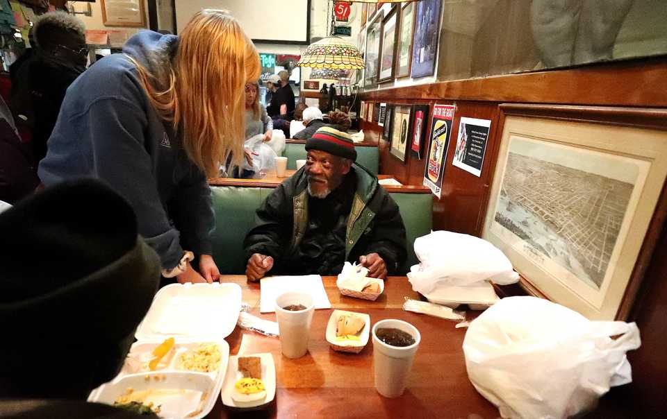 <strong>Joe Woolridge (center) speaks with a volunteer at Westy's while receiving a free Thanksgiving meal. Westy's has been providing a free Thanksgiving meal for 15 years, and with the help of Operation BBQ Relief and Lindenwood Christian Church they're able to serve hundreds of meals to those in need.</strong> (Houston Cofield/Daily Memphian)