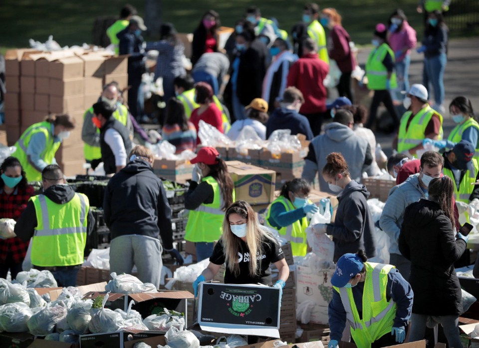 <strong>Some 80 volunteers from Las Americas and Nueva Direccion Church rush to distribute food for 1,000 families on April 10, 2020, from the Mid-South Christian College campus.</strong> (Jim Weber/Daily Memphian)