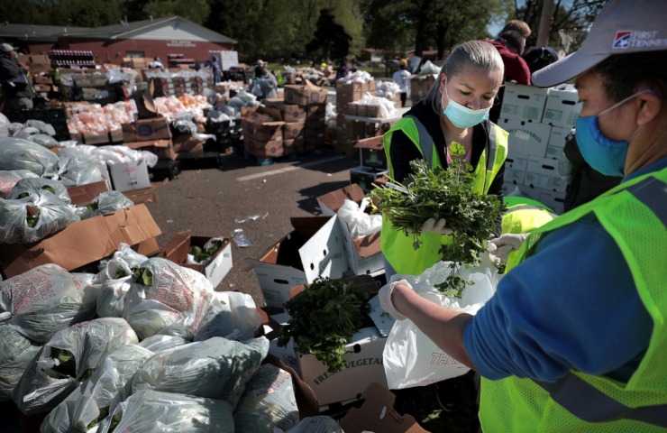 <strong>Maria Lozano (left) and Otilia Wood portion out fresh parsley as some 80 volunteers from Las Americas and Nueva Direccion Church rush to distribute food for 1,000 families on April 10, 2020, from the Mid-South Christian College campus.</strong> (Jim Weber/Daily Memphian)
