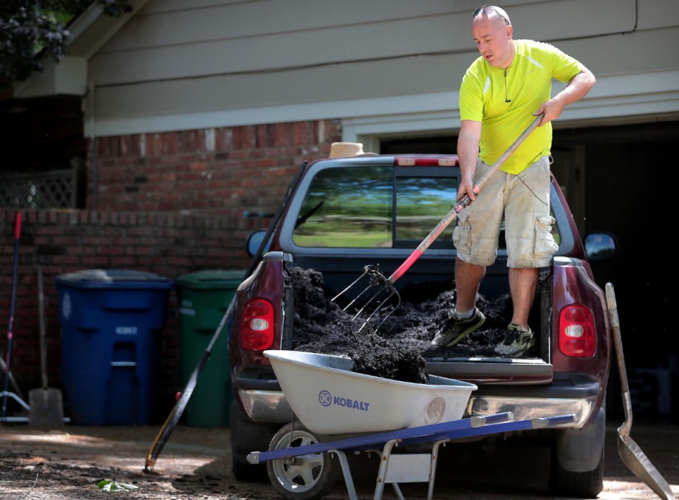 <strong>Scott Briggs shovels mulch out of the back of his borrowed truck while planting hydrangeas at a client's home in East Memphis on April 11, 2020. Briggs is a laid-off bartender who, rather than pulling unemployment, decided to start a lawn-care business called Laid Off Lawn Care, which has exploded with business over the first two weeks.</strong> (Jim Weber/Daily Memphian)