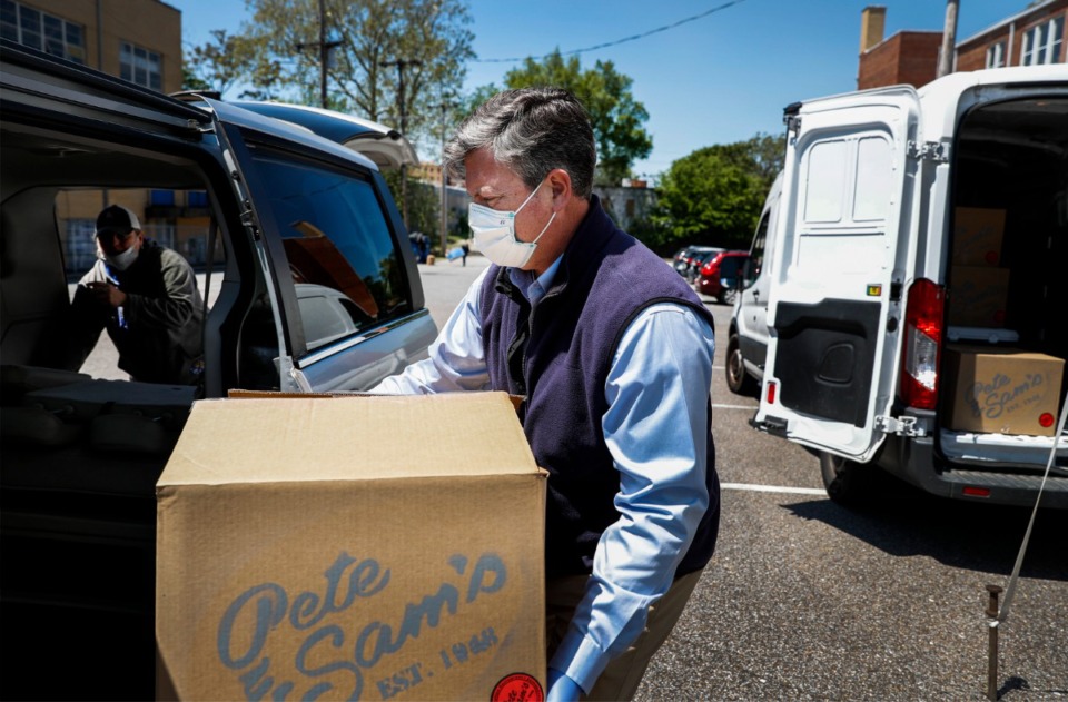 <strong>Catholic Charities of West Tennessee Executive Director Kelley Henderson (middle) helps case manager Shannon Privett (left) load a car with spaghetti dinners donated from Pete and Sam&rsquo;s restaurant on Wednesday, April 15, 2020. Pete and Sam&rsquo;s donated 560 meals that will be apart of a care package delivered to 160 formerly homeless families. Some of the donated meals will also be handed out to several area churches, who also help feed the needy and homeless families.</strong> (Mark Weber/Daily Memphian)