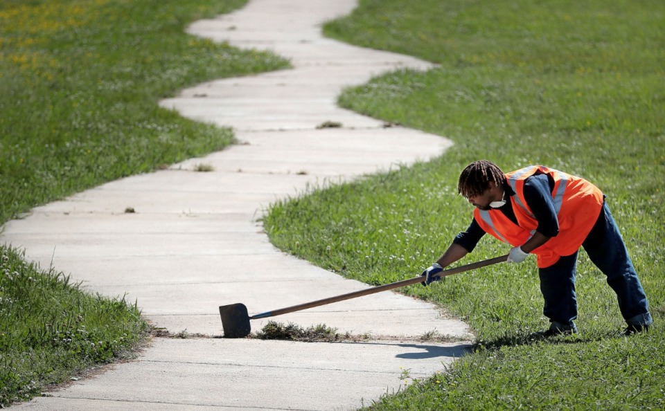 <strong>Sheldon Green of the Heights CDC cleans weeds out of the walking path while performing maintenance at Treadwell Park on April 15, 2020. The Heights CDC is struggling to maintain a full workforce even as it launches a COVID-19 response fund to help neighborhood residents struggling to pay bills.</strong> (Jim Weber/Daily Memphian)